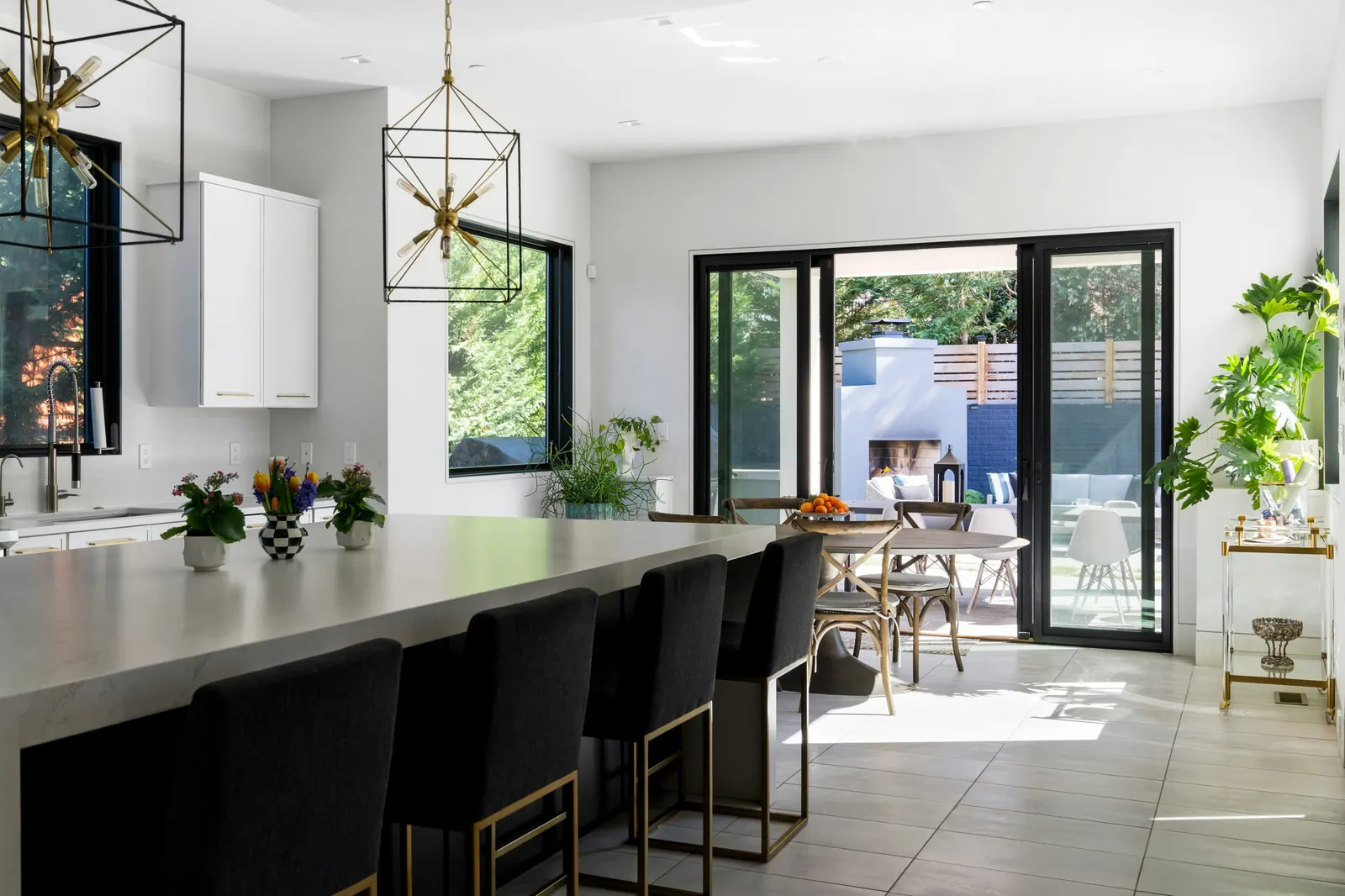 Cocina abierta con isla, taburetes y puertas correderas de cristal