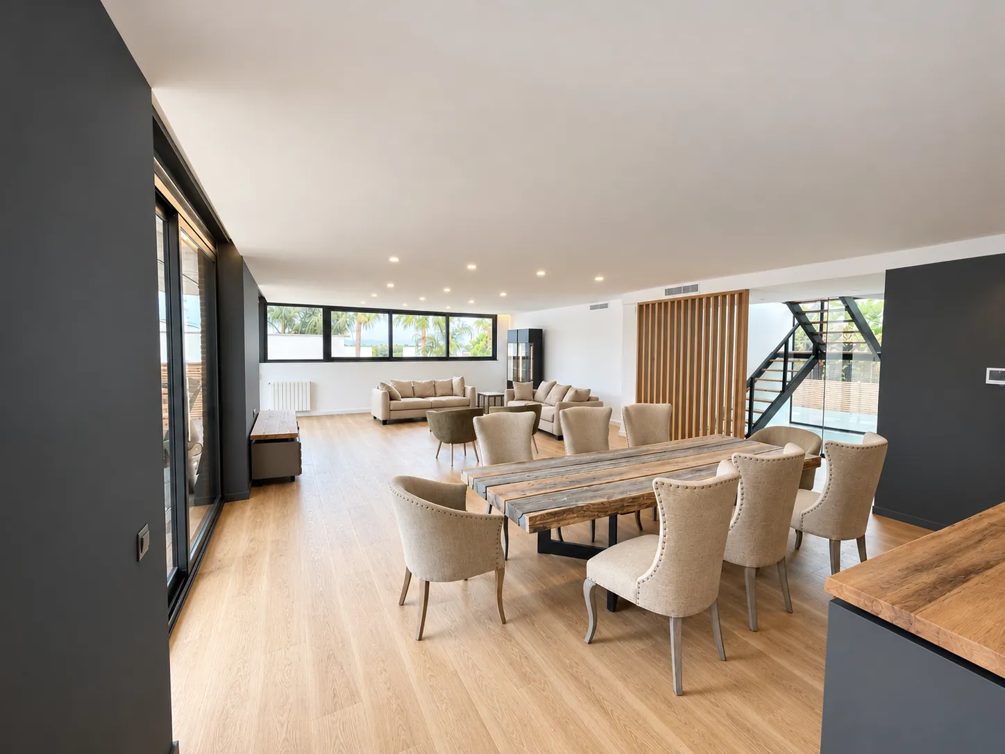 Open-plan living and dining room with wood flooring, dining table and large windows