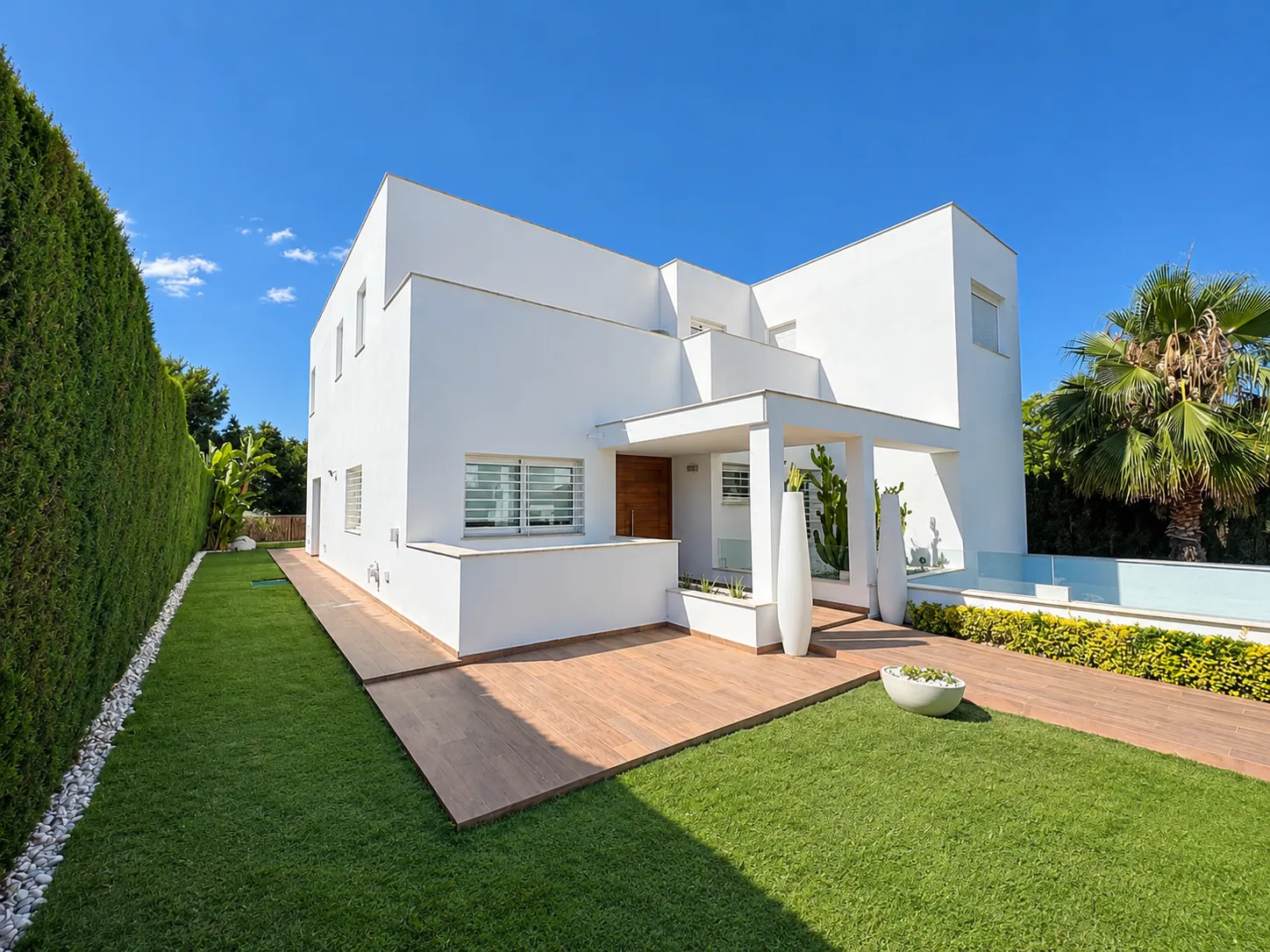 White house façade with a lawn garden, ceramic paving and a pool